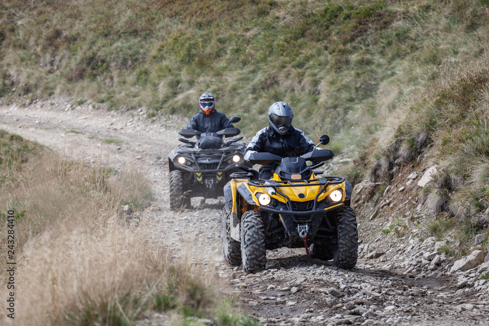 Front view of quad bikes zipping along a country road.