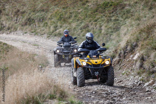 Front view of quad bikes zipping along a country road.