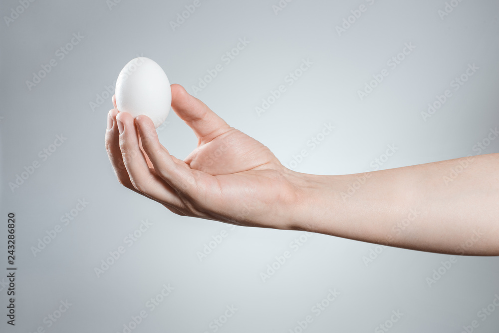 Hand holding an egg on gray background Hand holding an egg on gray background