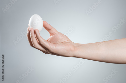 Hand holding an egg on gray background
