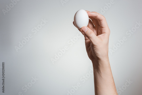 Hand holding an egg on gray background