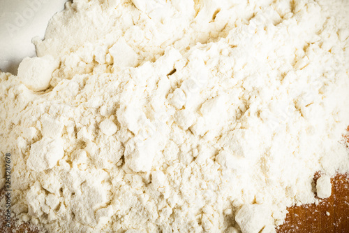 Pile of white wheat flour is scattered on an old worn cutting board. Toned