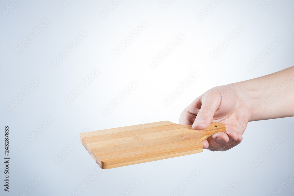 Hand holding a cute small cutting board  on gray background