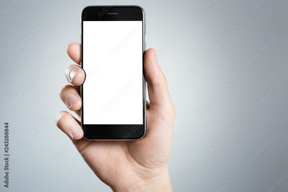 Hand holding black smartphone on gray background Hand holding black smartphone on gray background