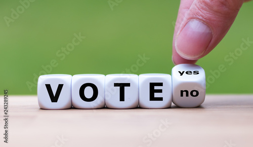 To Vote or Not to Vote? Hand turns a dice and changes the word "no" to "yes (or vice versa)