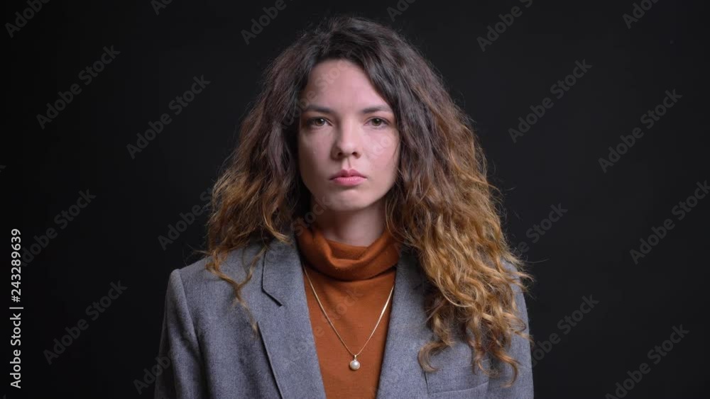 Closeup portrait of beautiful young caucasian female in formal clothings looking straight at the camera with neutral facial expression Closeup portrait of beautiful young caucasian female in formal clothings looking straight at the camera with neutral facial expression