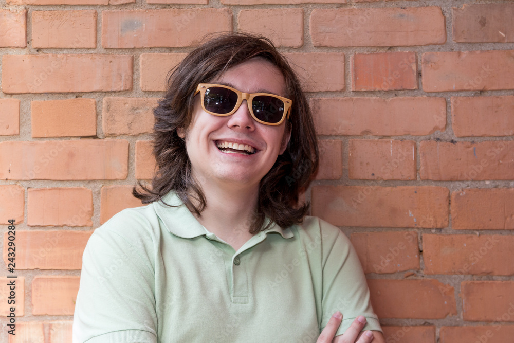 Portrait of teenager with long hair smiling and wearing sunglasses against wall. Portrait of teenager with long hair smiling and wearing sunglasses against wall.