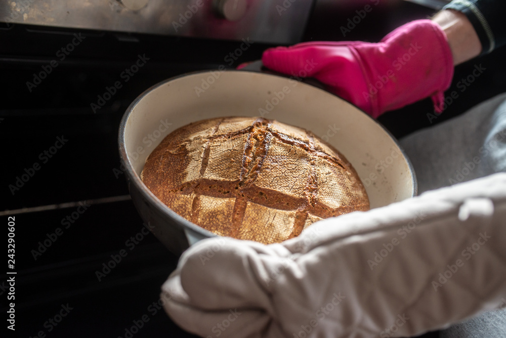 Fototapeta premium Closeup of a man taking a freshly baked home made bread out of the oven