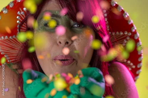 Carnaval Brazil. Blowing Confetti. Carnival concept, fun and party. Portrait of brazilian red hair woman with green make up mask.