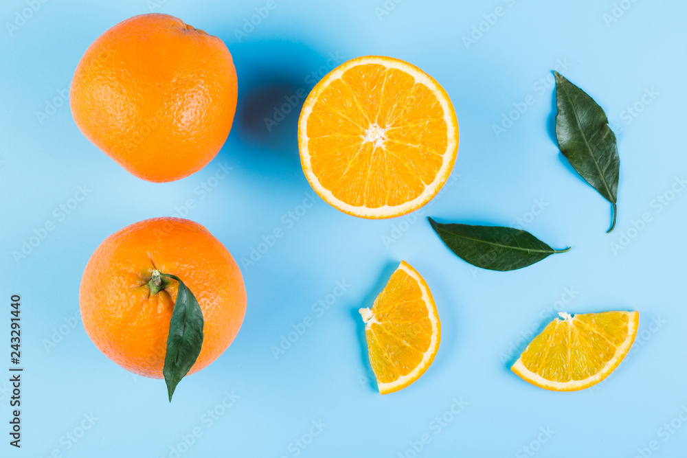 Slices of orange with leaves on blue background. Flat lay, top view. Slices of orange with leaves on blue background. Flat lay, top view.