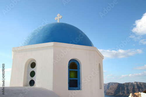 Traditional white church with a Blue dome, perched on the side of the cliff, Oia, Santorini, Greece.
