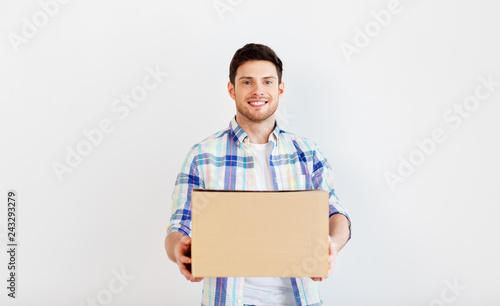 people and moving to new place concept - happy man holding cardboard box