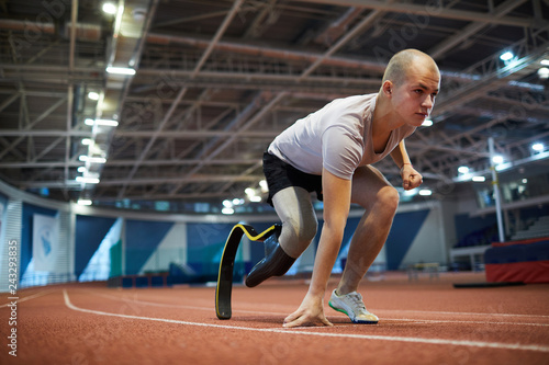 Young paralympic competitor of marathon leaning by start line on race track before running