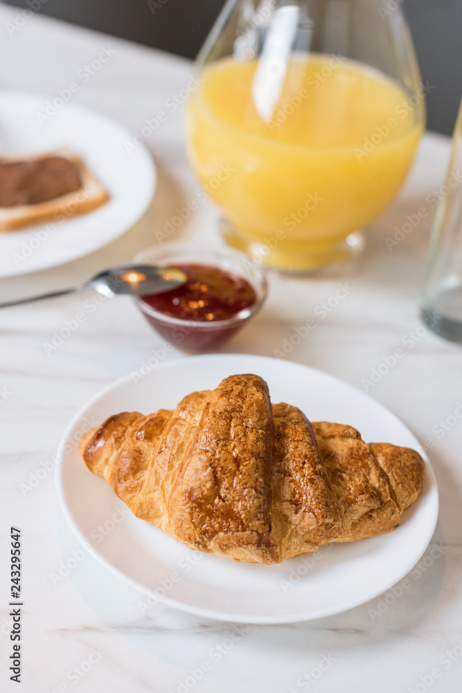 selective focus of tasty croissant with jam and orange juice in jug on background