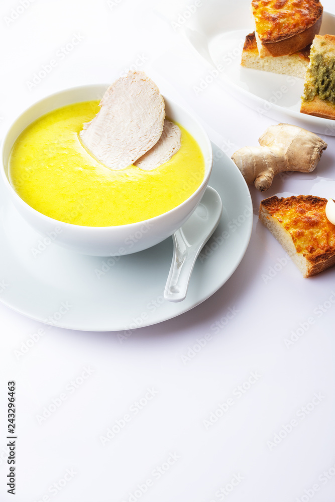 Chicken cream soup with a curry and pieces of chicken meat. On a white background. Toasts with garlic and cheese. Close up. Selective focus. Chicken cream soup with a curry and pieces of chicken meat. On a white background. Toasts with garlic and cheese. Close up. Selective focus.