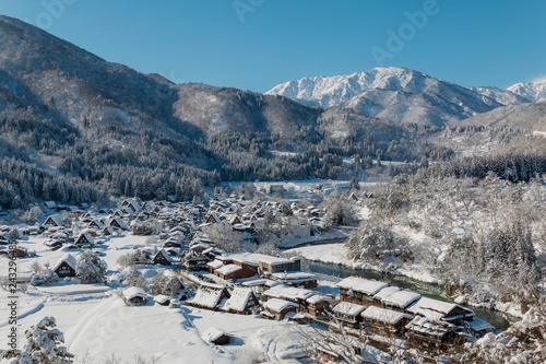 The panoramic viewpoint of Gassho houses in Shirakawago village with snow covered ground ,blue sky and mountains background at winter in Gifu,Japan.