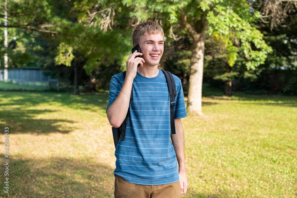 Teenager on his cellphone while standing in a city park on a summer day. Teenager on his cellphone while standing in a city park on a summer day.