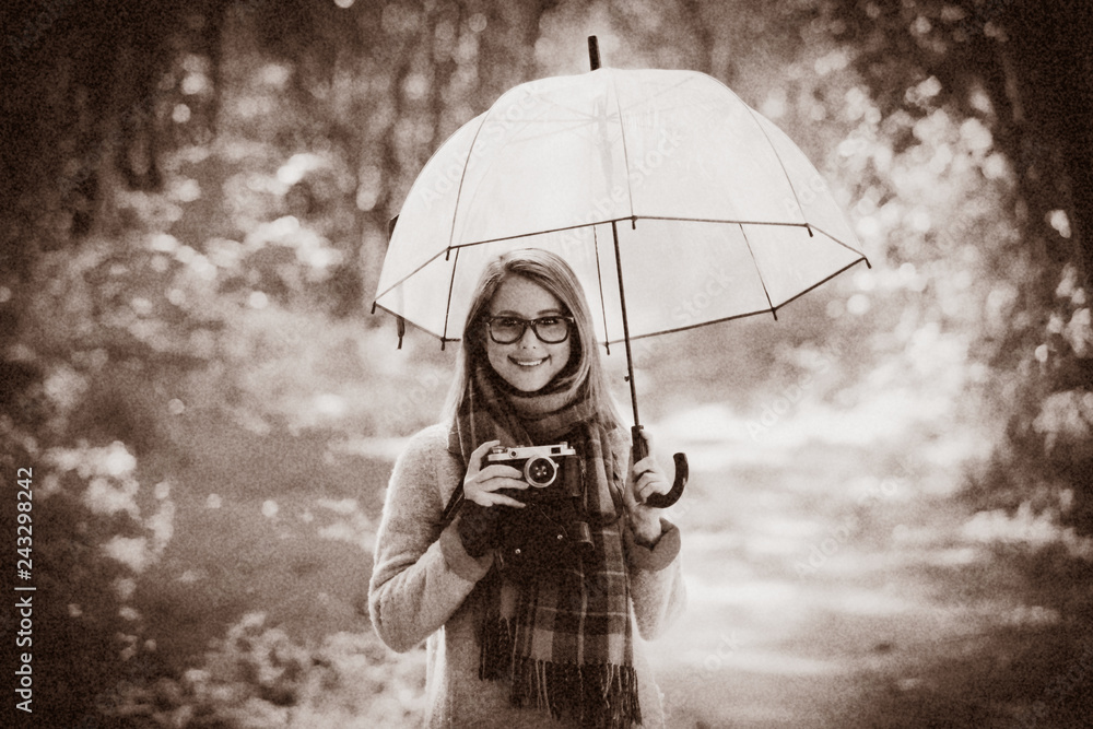 Young girl with umbrella and camera in park in autumn season
