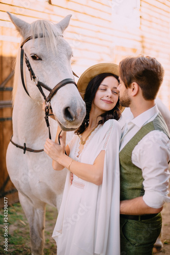 newlyweds look at each other holding horse