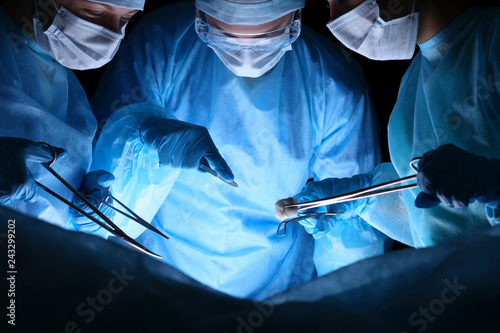 Fototapeta Group of surgeons in masks performing operation