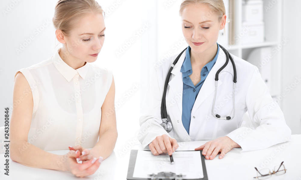 Doctor and patient talking in hospital office while sitting at the desk. Health care and client service in medicine Doctor and patient talking in hospital office while sitting at the desk. Health care and client service in medicine
