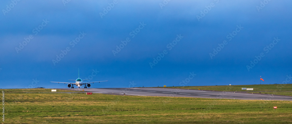 Passenger aircraft in the distance taxiing on the runway during evening time