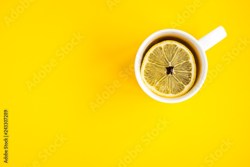 Mug of hot tea with lemon on yellow background. Catarrhal disease. Flu season.