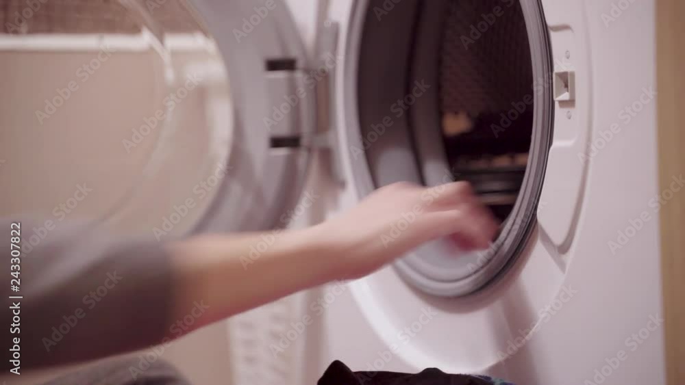 Woman loading laundry to the washing machine Woman loading laundry to the washing machine