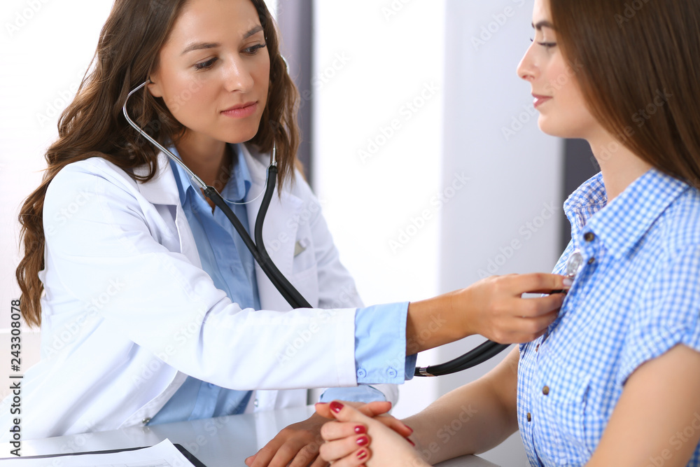 Doctor with a stethoscope in the hand examining her female patient. Health care, cardiology and medicine concepts Doctor with a stethoscope in the hand examining her female patient. Health care, cardiology and medicine concepts