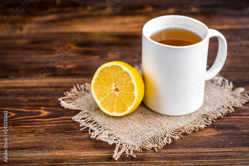 Mug of hot tea with lemon on wooden background. Catarrhal disease. Flu season.
