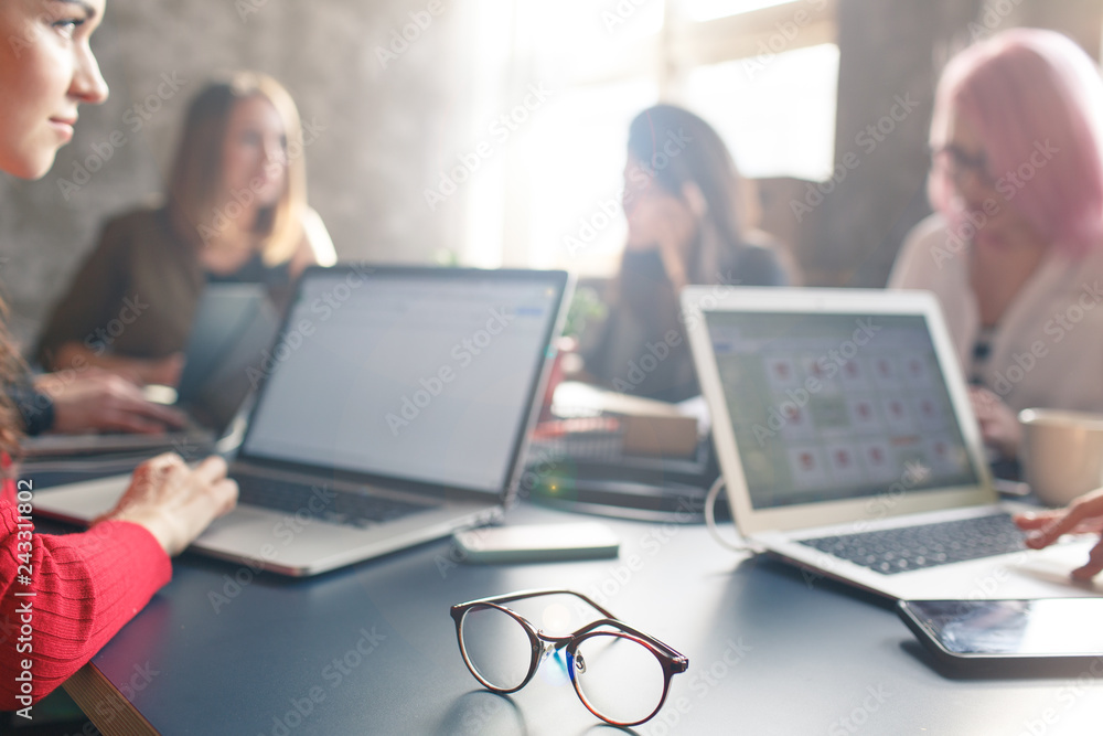 Employees discuss business issues in the office. A group of businesswomen talking at a table in the office Employees discuss business issues in the office. A group of businesswomen talking at a table in the office