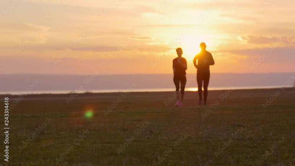 Group of runners training outdoors exercising at sunset on amazing nature landscape. Fit athletic family, man and woman working out for marathon run outside. Couple, male and female sport. Group of runners training outdoors exercising at sunset on amazing nature landscape. Fit athletic family, man and woman working out for marathon run outside. Couple, male and female sport.