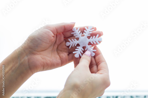 Female hands hold white snowflake on an isolated background close up