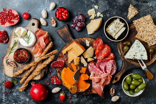 Appetizers table with italian antipasti snacks. Brushetta or authentic traditional spanish tapas set, cheese variety board over black stone background. Top view, flat lay