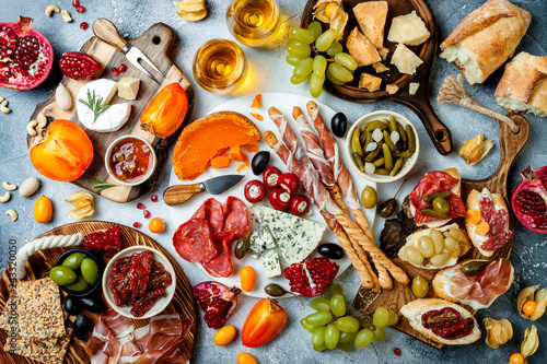 Appetizers table with antipasti snacks and wine in glasses. Brushetta or authentic traditional spanish tapas set, cheese and meat platter over grey concrete background. Top view © sveta_zarzamora