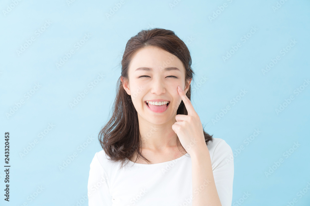 Fototapeta premium 舌を出す若い女性・ブルーバック