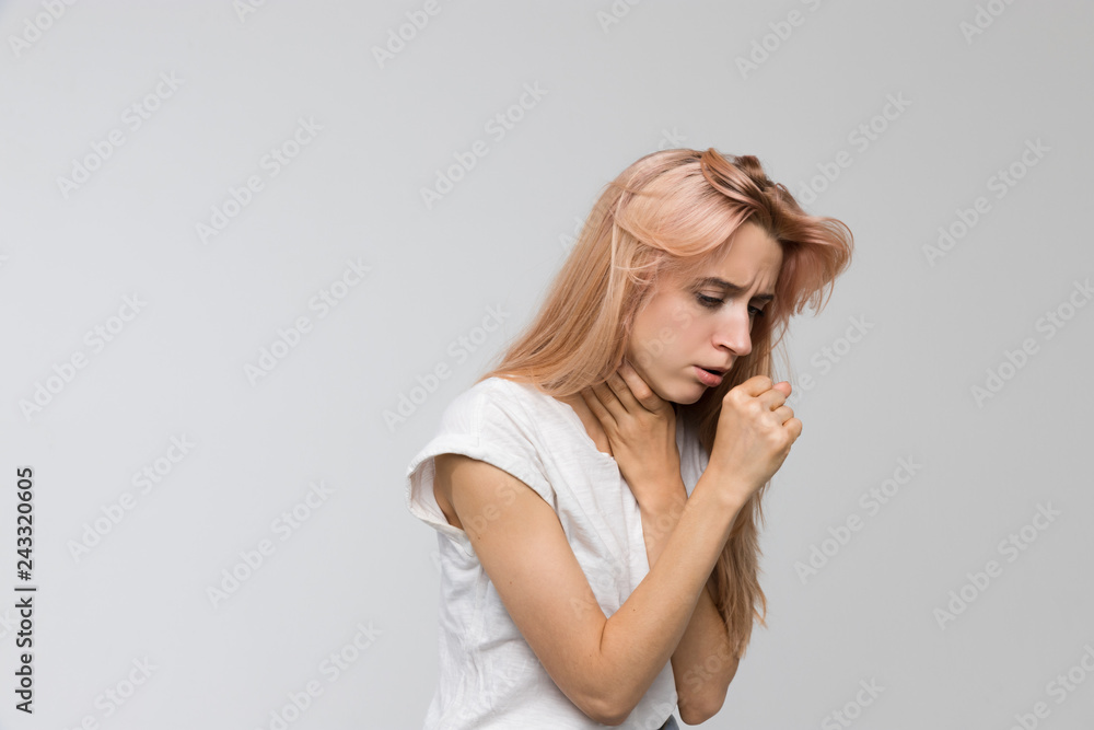 Studio portrait of young unhealthy coughing woman feeling the first symptoms of illness/suffers from cold and flu, coughing a lot, sore throat, feeling sick, medicine and healthcare concept.