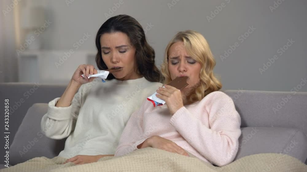Two depressed broken-hearted women eating chocolate, support after brake up Two depressed broken-hearted women eating chocolate, support after brake up