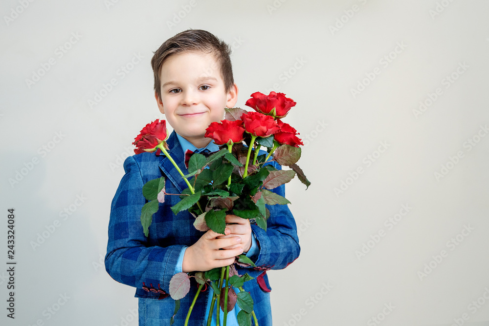 Adorable little boy in suit with bouquet of red roses on a light background Adorable little boy in suit with bouquet of red roses on a light background