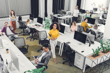 high angle view of multiracial young business people working with computers and documents in open space office