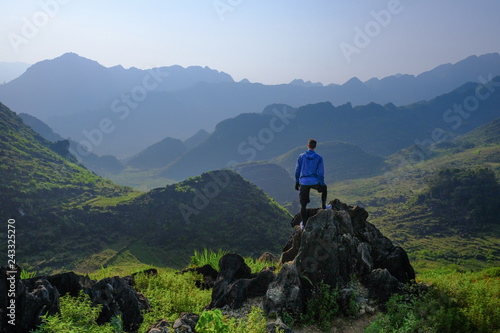 Backpacker standing on outcrop overlooking karst mountain scenery in the North Vietnamese region of Ha Giang / Dong Van