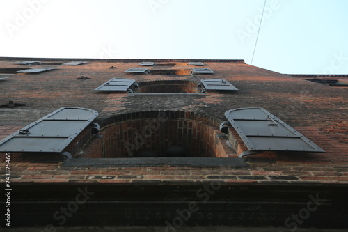 Bottom view of the building of brick which is connected by concrete with windows