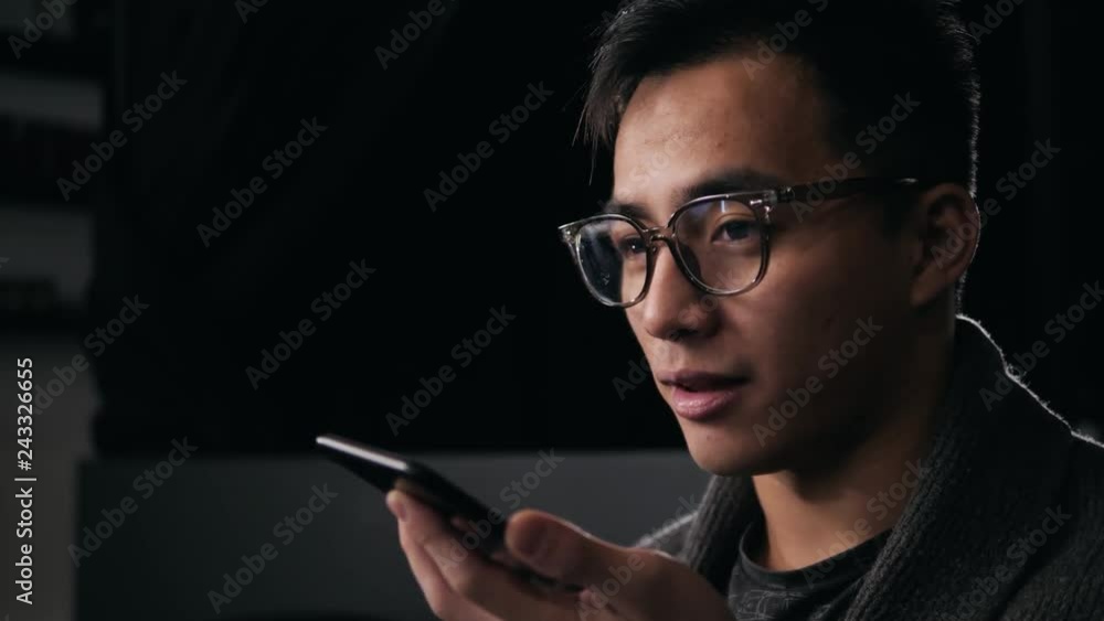 hands free calling with smart phone. Asian man korean voice recognition ai speech helper close up dark cafe office hands free calling with smart phone. Asian man korean voice recognition ai speech helper close up dark cafe office