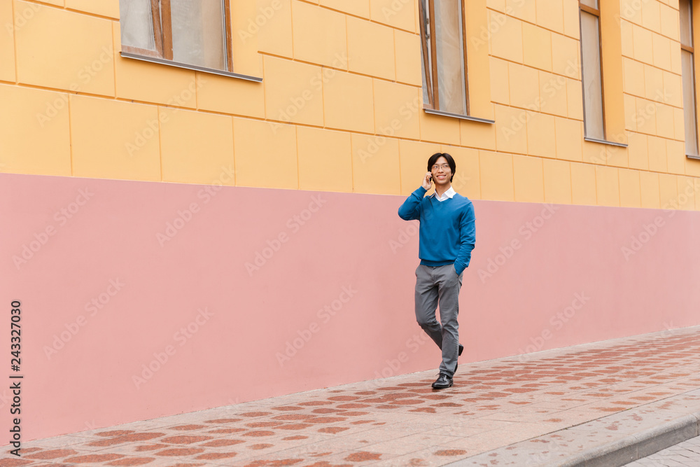 Smiling young asian business man talking on mobile phone Smiling young asian business man talking on mobile phone
