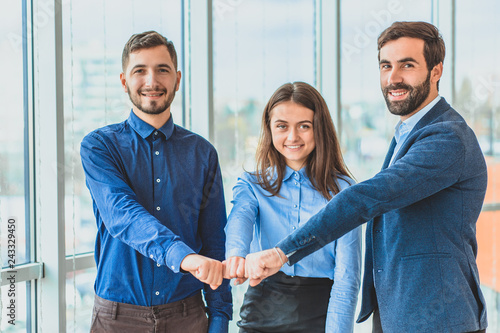 Three business people placing a contract put a hand on hand.