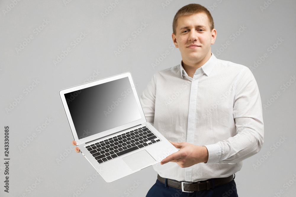 young man with laptop with an empty screen in his hands is isolated on light background young man with laptop with an empty screen in his hands is isolated on light background