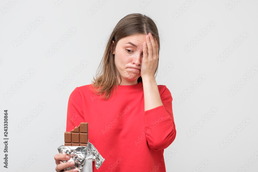 Sad young woman tired of diet restrictions holding sweet chocolate Sad young woman tired of diet restrictions holding sweet chocolate