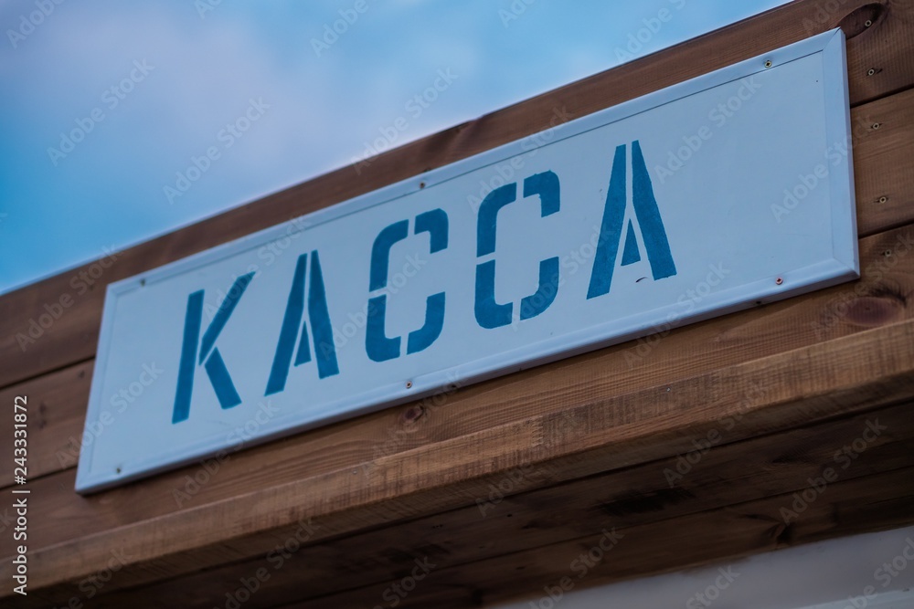 A sign of the ticket office in Russia. Purchase tickets for entertainment. Inscription in Russia means Cash Desk. Blue letters on wooden background. A sign of the ticket office in Russia. Purchase tickets for entertainment. Inscription in Russia means Cash Desk. Blue letters on wooden background.