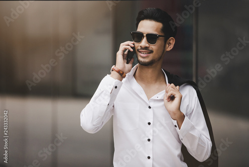 Young executive businessman using a mobile phone in the business district with skyscrapers buildings background