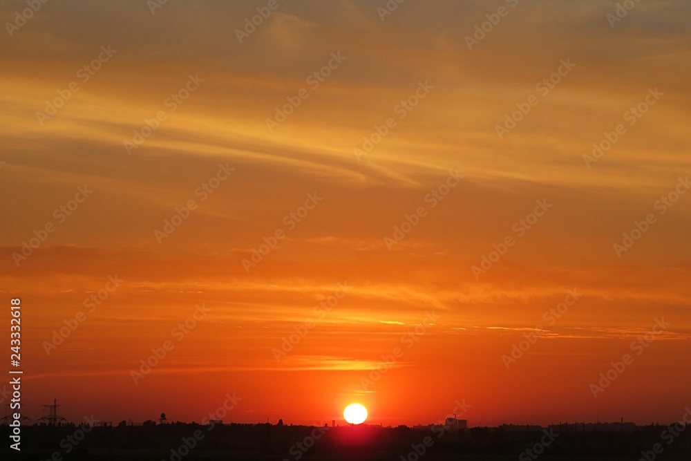 Beautiful fiery orange sunset background over the city, the sun sets over the horizon
